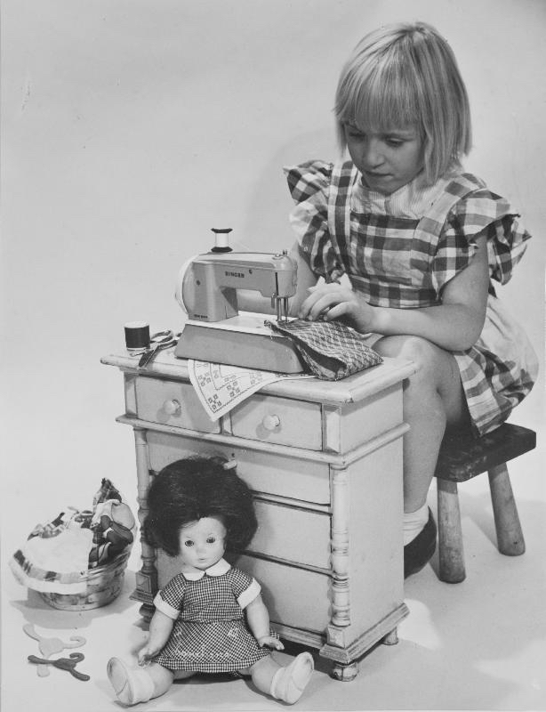 Tyttö ompelee nukenvaatteita