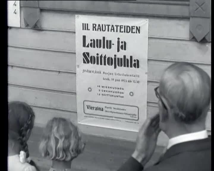 Kuva vanhasta elokuvasta - mies katsoo laulujuhlajulistetta